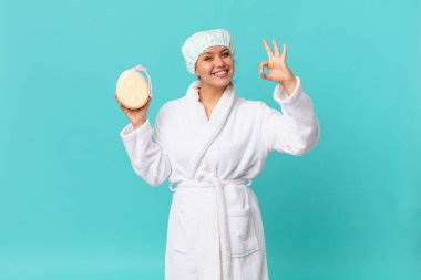 Genç, güzel bir kadın kendini mutlu hissediyor. Onayını gösteriyor. Güzel bir jest yapıyor ve duştan sonra bornoz giyiyor.