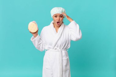 Genç, güzel bir kadın mutlu, şaşkın ve şaşırmış görünüyor ve duştan sonra banyo cübbesi giyiyor.