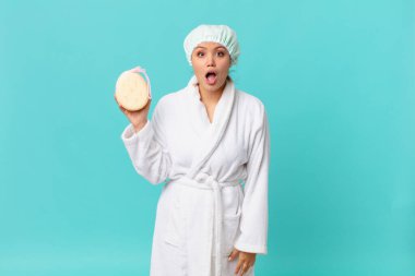 Genç ve güzel bir kadın çok şaşırmış ya da şaşırmış görünüyor ve duştan sonra bornoz giyiyor.