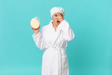 Genç, güzel bir kadın şok olmuş, korkmuş ya da korkmuş görünüyor. Yüzü elle örtülmüş ve duştan sonra banyo bornozu giyiyor.