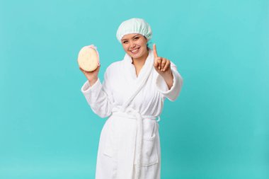 Genç, güzel bir kadın gülümsüyor ve arkadaş canlısı görünüyor. Bir numarayı gösteriyor ve duştan sonra banyo cübbesi giyiyor.