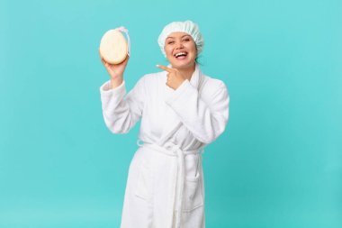 Genç ve güzel bir kadın heyecanlı ve şaşırmış görünüyor. Yan tarafı gösteriyor ve duştan sonra banyo cübbesi giyiyor.