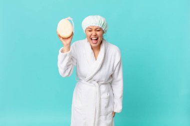 Genç ve güzel bir kadın agresif bir şekilde bağırıyor, çok kızgın görünüyor ve duştan sonra banyo cübbesi giyiyor.