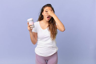 Genç, güzel bir kadın şok olmuş, korkmuş ya da dehşete düşmüş görünüyor. Yüzü elle kaplanmış ve elinde kahve tutuyor.