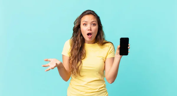 Młoda Ładna Kobieta Czuje Się Bardzo Zszokowany Zaskoczony Trzymając Smartfon — Zdjęcie stockowe