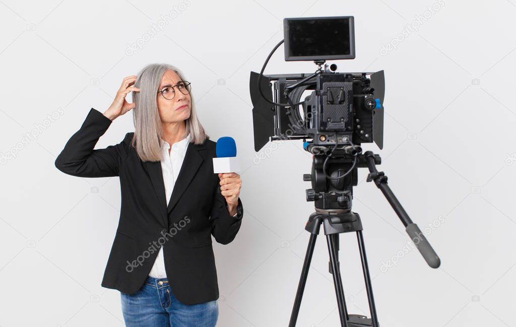 middle age white hair woman feeling puzzled and confused, scratching head and holding a microphone. television presenter concept