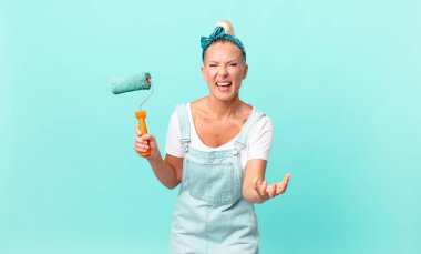 Güzel sarışın kadın umutsuz görünüyor, sinirli ve stresli ve duvar boyuyor.