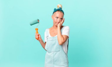 Güzel sarışın kadın sıkılmış, hayal kırıklığına uğramış ve uykulu. Yorucu bir günün ardından duvar boyuyor.