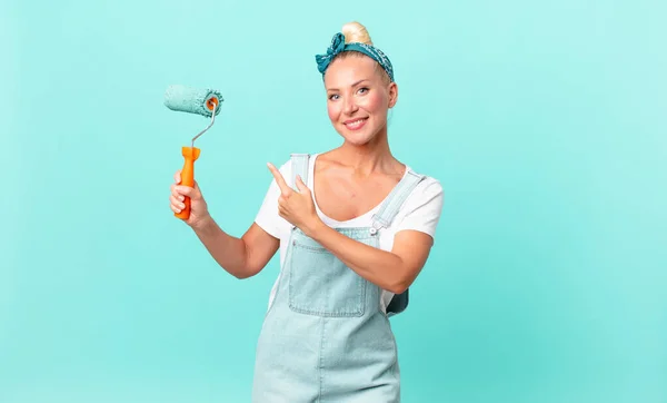 Bonita Mujer Rubia Sonriendo Alegremente Sintiéndose Feliz Señalando Lado Pintando — Foto de Stock