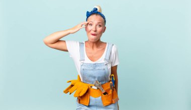 Güzel sarışın kadın mutlu, şaşkın, şaşırmış ve ev konseptini tamir ediyor.