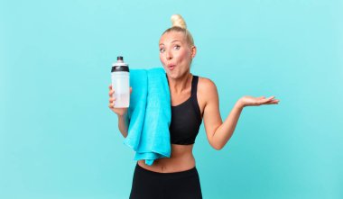 Güzel sarışın kadın şaşırmış ve şok olmuş görünüyor. Çenesi düşmüş ve elinde bir nesne var. fitness konsepti
