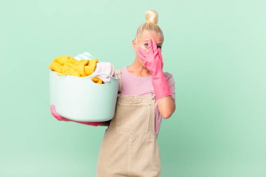 Güzel sarışın kadın şok olmuş, korkmuş ya da korkmuş görünüyor, yüzünü el yıkama konseptiyle kapatıyor.