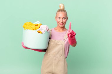 Güzel sarışın kadın gülümsüyor ve arkadaş canlısı görünüyor. Bir numaralı çamaşır yıkama konseptini gösteriyor.