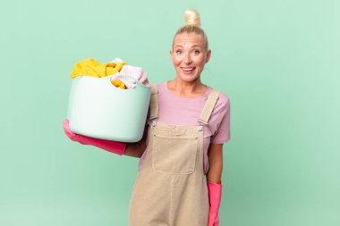 Güzel sarışın kadın mutlu görünüyor ve çamaşır yıkama konseptini hoş bir şekilde şaşırtıyor.