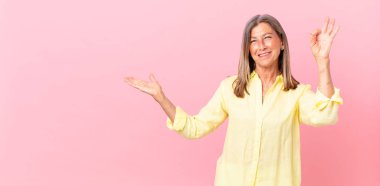 Güzel orta yaşlı bir kadın kendini mutlu hissediyor. Onayını iyi bir hareketle gösteriyor.