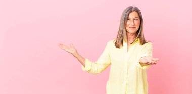 Sevimli orta yaşlı bir kadın mutlu bir şekilde gülümsüyor ve bir konsept sunuyor.