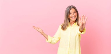 Güzel orta yaşlı bir kadın gülümsüyor ve arkadaş canlısı görünüyor.