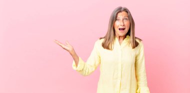 Güzel orta yaşlı bir kadın mutlu ve hoş bir şekilde şaşırmış görünüyor.