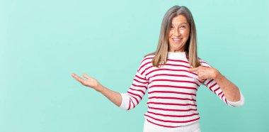 Güzel orta yaşlı bir kadın mutlu hissediyor ve heyecanlı bir şekilde kendini işaret ediyor.