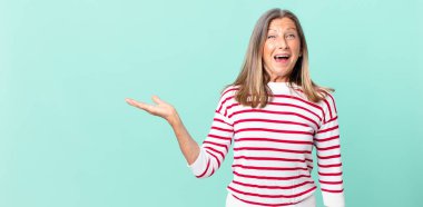 Güzel orta yaşlı bir kadın mutlu ve hoş bir şekilde şaşırmış görünüyor.