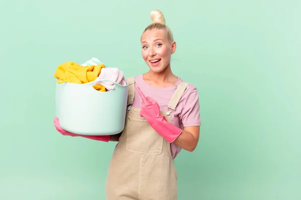 Pretty Blond Woman Looking Excited Surprised Pointing Side Washing Clothes — Stock Photo, Image