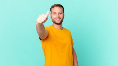 handsome blonde man feeling proud,smiling positively with thumbs up