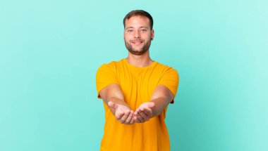 handsome blonde man smiling happily with friendly and  offering and showing a concept