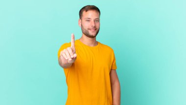 handsome blonde man smiling proudly and confidently making number one