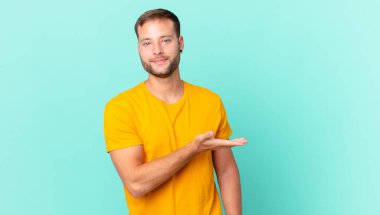 handsome blonde man smiling cheerfully, feeling happy and showing a concept