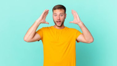 handsome blonde man screaming with hands up in the air