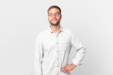 handsome blonde man smiling happily with a hand on hip and confident