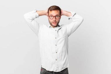 handsome blonde man feeling stressed, anxious or scared, with hands on head