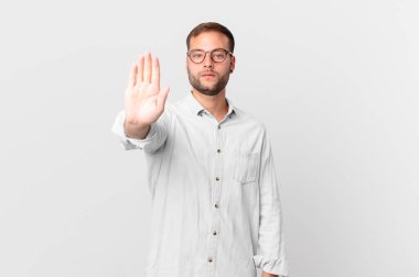handsome blonde man looking serious showing open palm making stop gesture