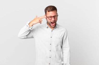 handsome blonde man looking unhappy and stressed, suicide gesture making gun sign