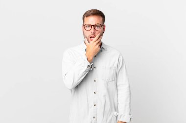 handsome blonde man with mouth and eyes wide open and hand on chin