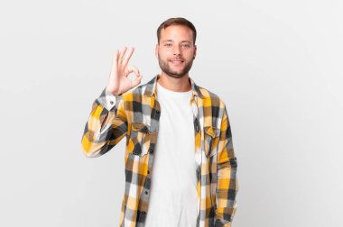 handsome blonde man feeling happy, showing approval with okay gesture