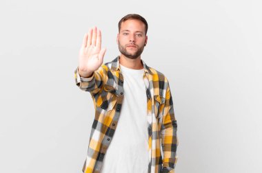handsome blonde man looking serious showing open palm making stop gesture