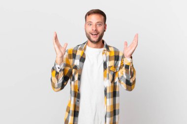 handsome blonde man feeling happy and astonished at something unbelievable