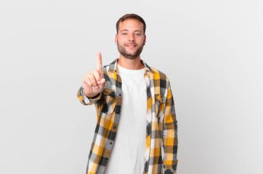 handsome blonde man smiling proudly and confidently making number one