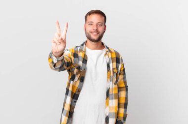 handsome blonde man smiling and looking friendly, showing number two