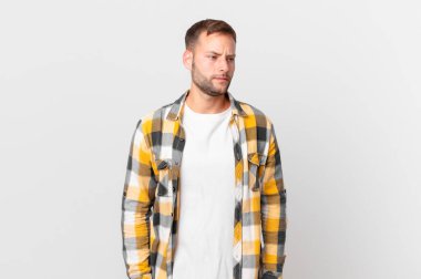 handsome blonde man feeling sad, upset or angry and looking to the side