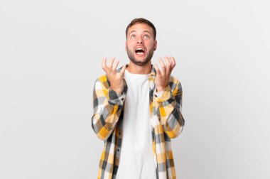 handsome blonde man looking desperate, frustrated and stressed
