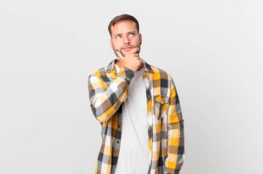 handsome blonde man thinking, feeling doubtful and confused