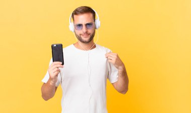 looking arrogant, successful, positive and proud, listening music with headphones and a smartphone