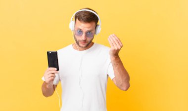 making capice or money gesture, telling you to pay, listening music with headphones and a smartphone