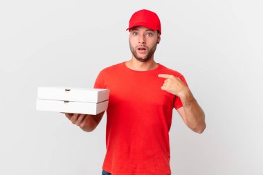 Pizza dağıtan adam şok olmuş ve ağzı açık, kendini işaret ederek şaşırmış görünüyor.
