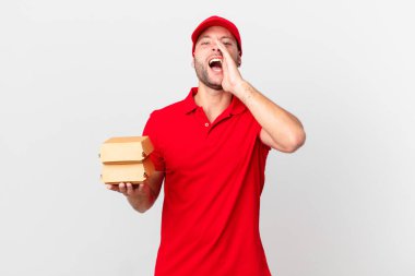 Hamburger dağıtan adam kendini mutlu hissediyor, elleri ağızda bağırıyor.