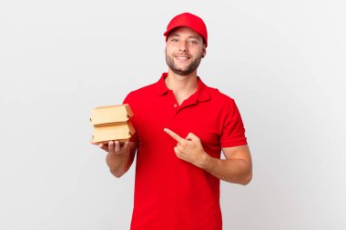 Hamburger dağıtan adam neşeyle gülümsüyor, mutlu hissediyor ve bir tarafı işaret ediyor.