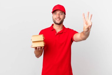 Hamburger dağıtan adam gülümsüyor ve arkadaş canlısı görünüyor.