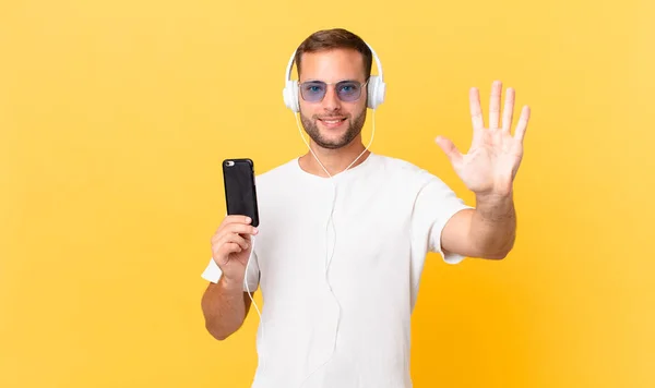 Smiling Looking Friendly Showing Number Five Listening Music Headphones Smartphone — Stockfoto